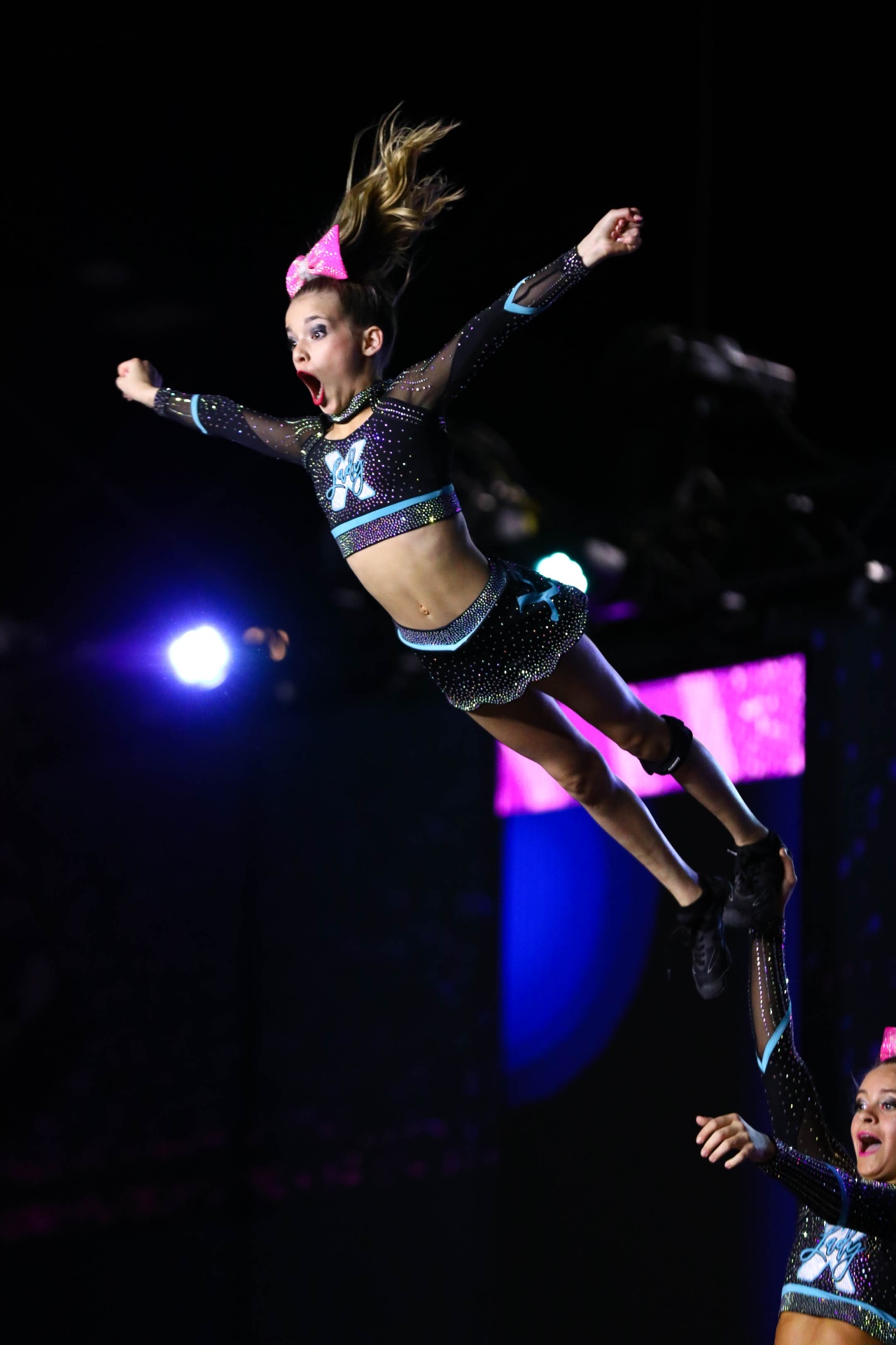 Cheer athlete mid-air during a competition routine